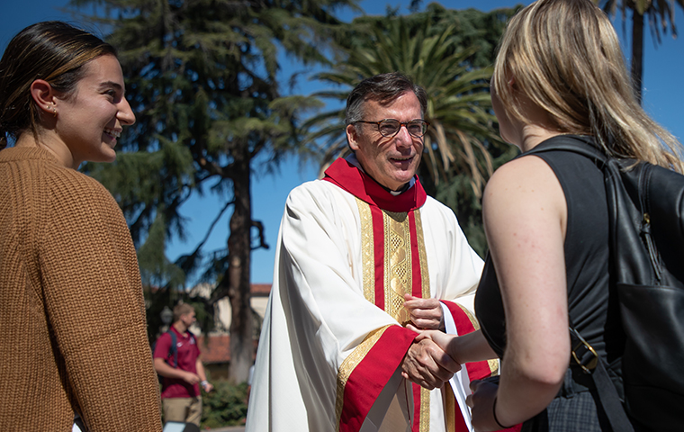 Fr. Kevin OBrien shakes hands outside the Mission Church following the Mass of the Holy Spirit