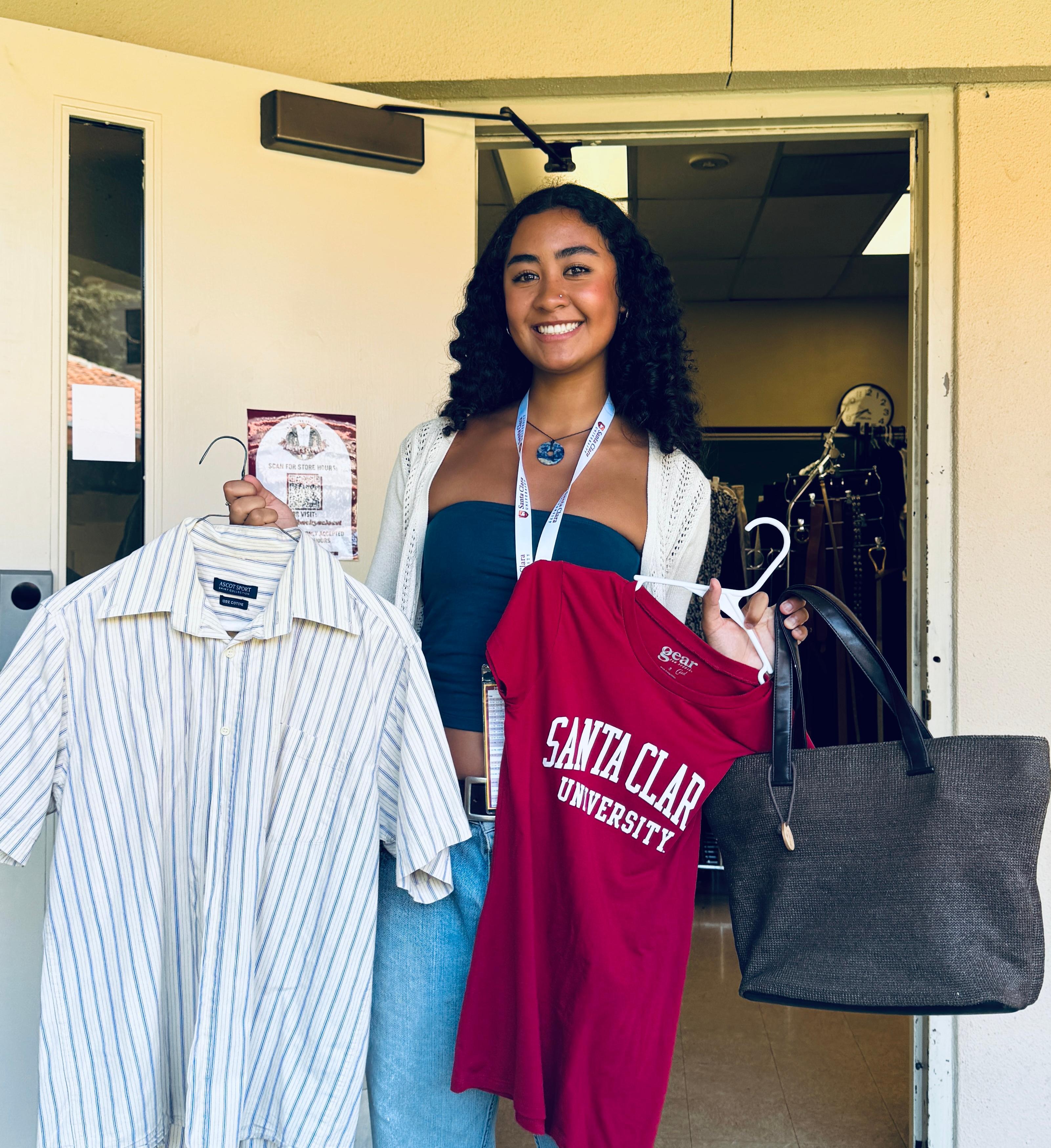 A smiling student holding clothing found at Buckys Closet