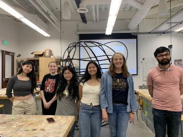 Five students and a faculty in front of artwork