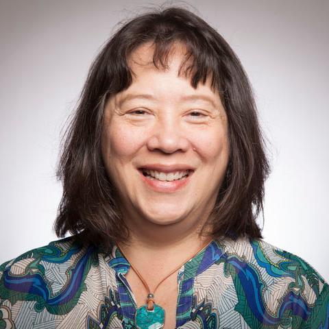 A woman smiling in a portrait with a patterned top.