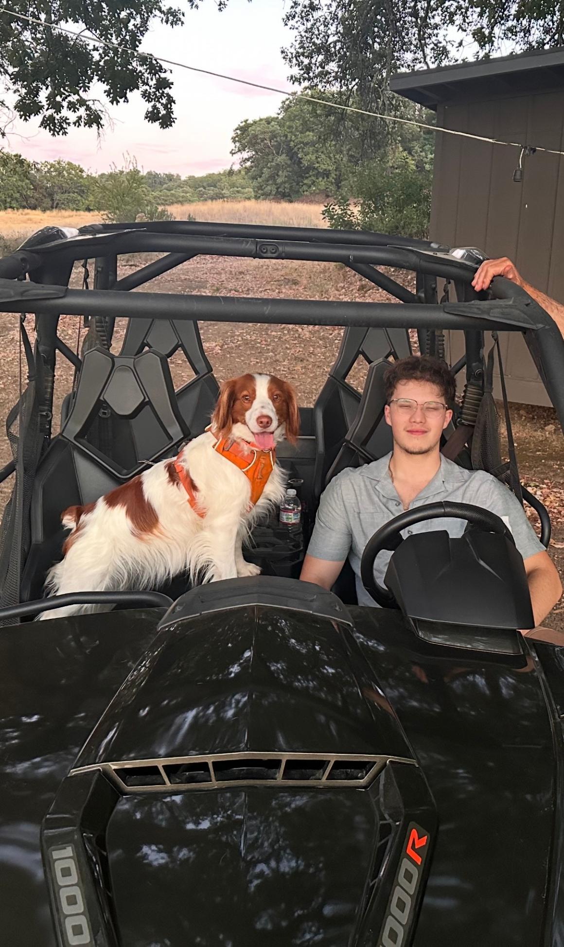Tyler Pineda at the wheel with his dog in passenger seat.