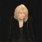 A person in black clothing against a black background.