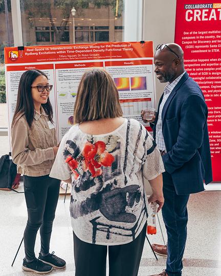 Kafui Dzirasa with 2 female students in front of their poster 
