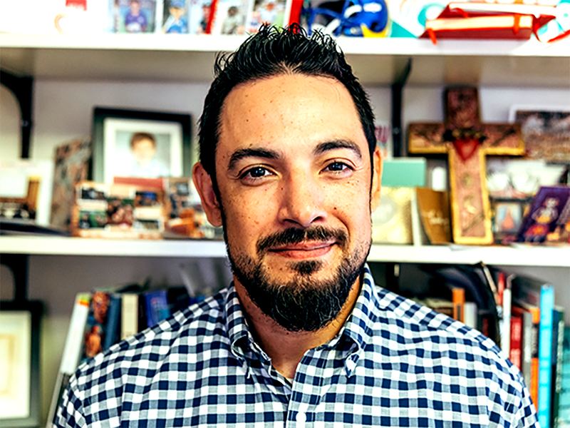 Cruz Medina with shelves full of photos and books in the background