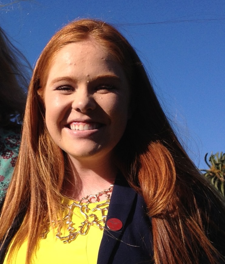 A person smiling against a clear blue sky.