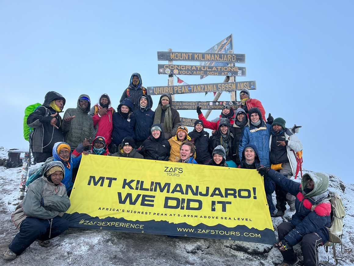 Sammi Bennett (center, black jacket and blue headband) with gap-year students at the summit of Kilimanjaro.
