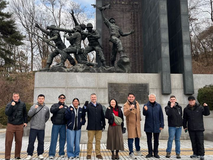 Group standing below statue of soldiers in battle