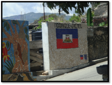 Concrete wall with a Haitian flag mural and text Haiti above it.