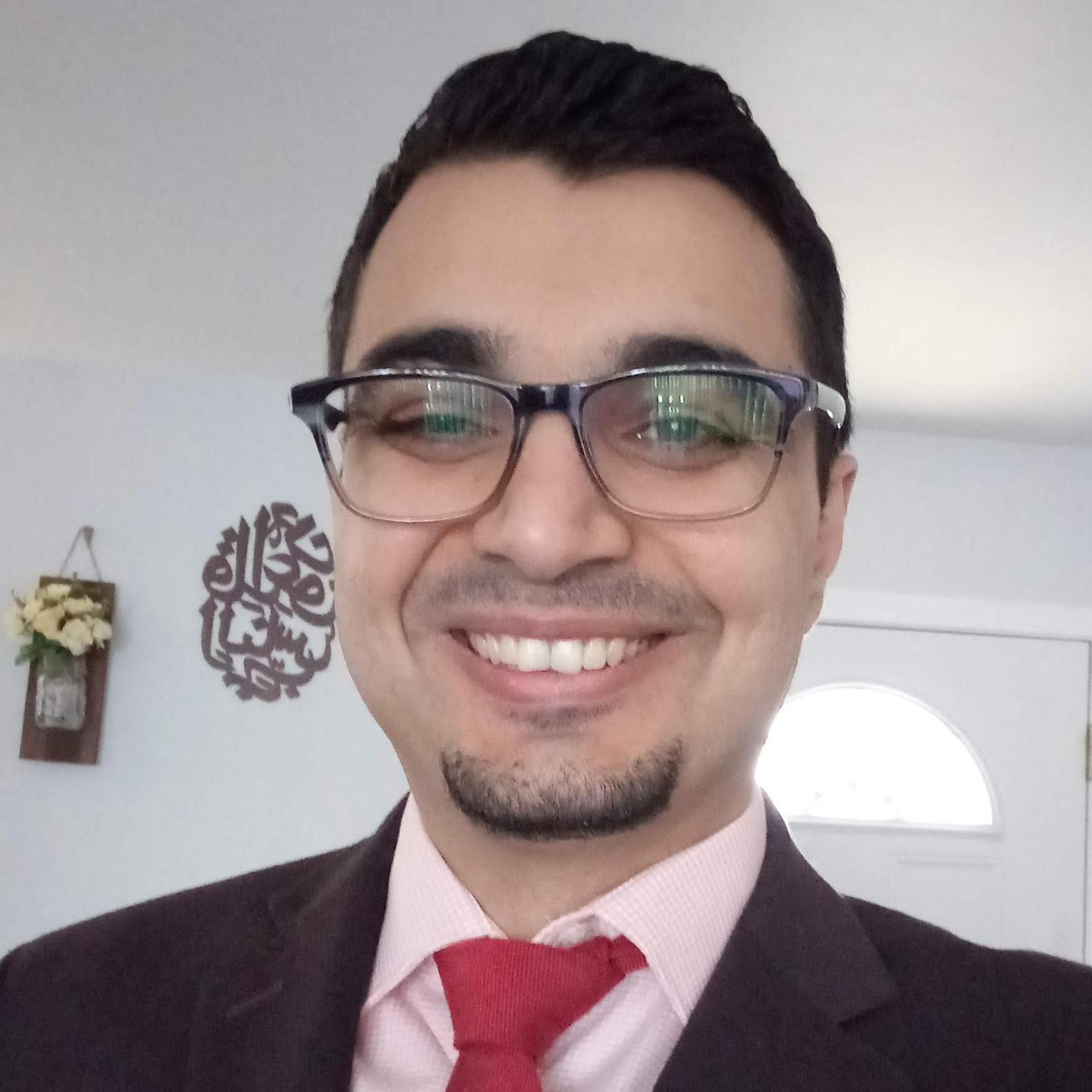 A person in a suit with a red tie smiling.