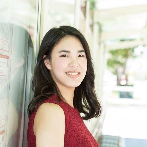 A woman in a red top smiling outdoors.