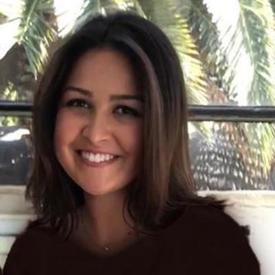 Smiling woman in front of palm trees and railing.