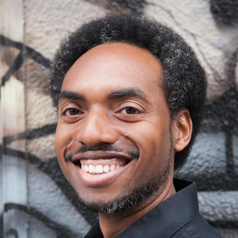 A smiling person in front of graffiti art.