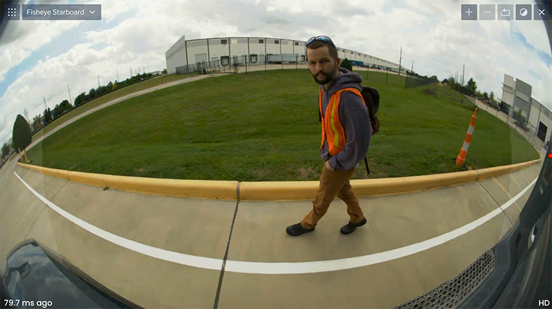 Fish eye view of Craig Benko walking on the side of a road.