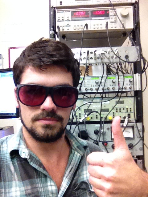 Bryan Berggren standing in front of a rack of equipment and signaling a thumbs up.