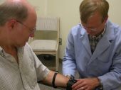 One person attaching a device to another persons arm.