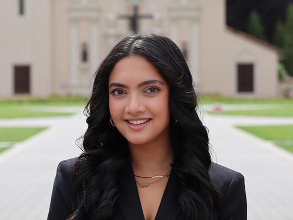 A female student wearing black standing in front of the Santa Clara Mission Church