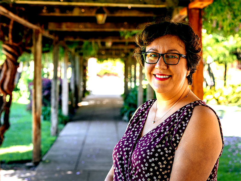 Pearl Barros standing next to the covered path next to Mission Santa Clara.