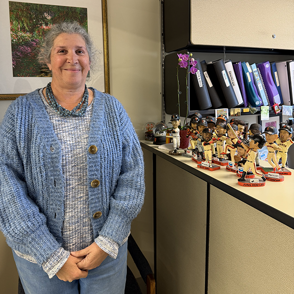 Vicky Gonalez standing next to her Giants bobble heads.