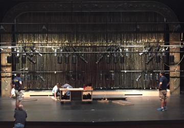 A dimly lit stage with hanging lights and equipment. 
