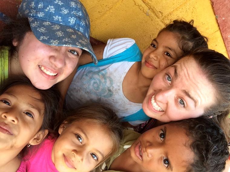 Group of smiling people huddled together under colorful fabric. Teatro Catalina 2015.