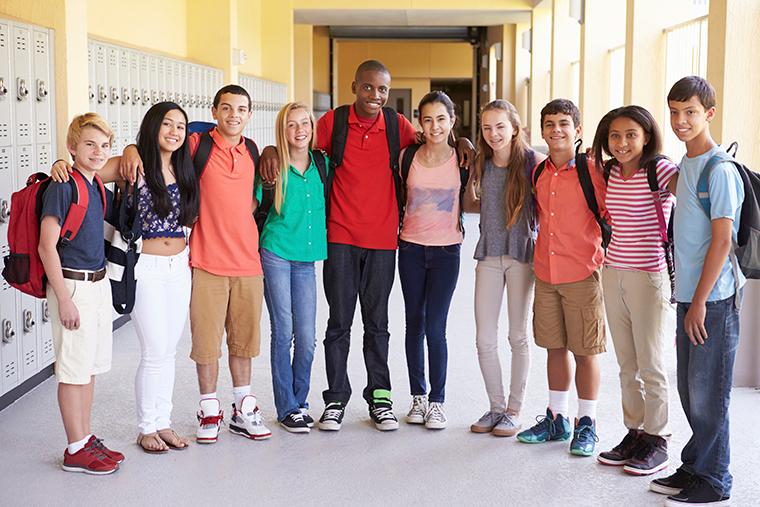 Students with arms around each others shoulders in school hallway 
