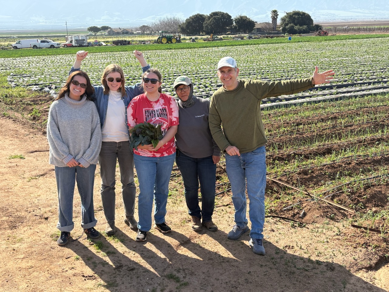 People posing in front of farm