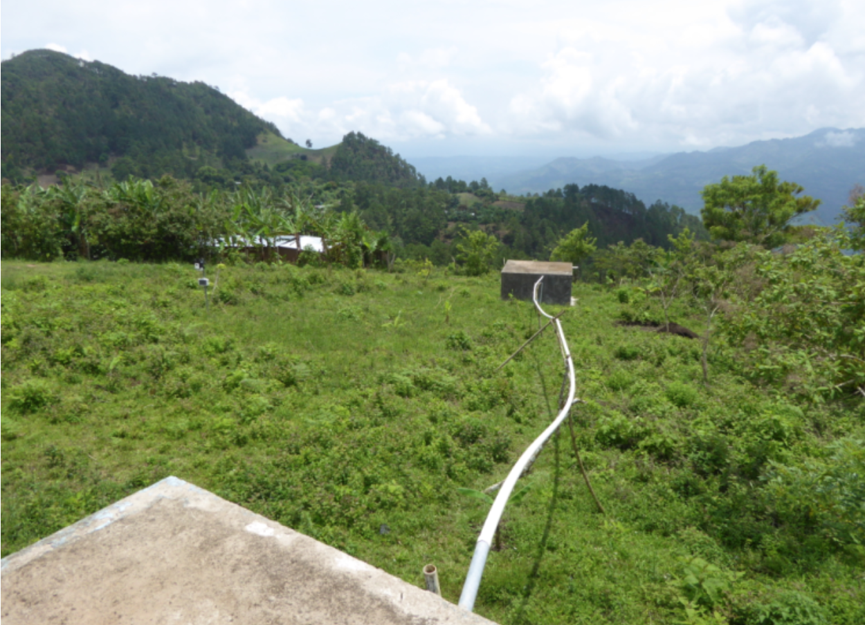 A white pipe running across a lush green hillside