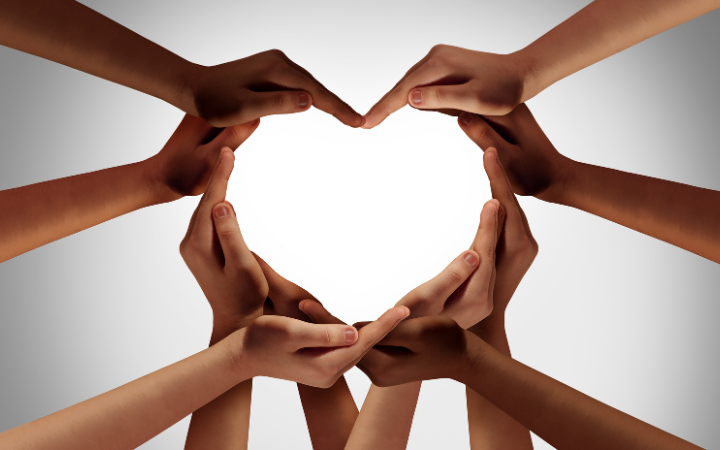 Ten hands form a heart representing the Santa Clara University three Cs: Competence, Compassion, and Conscience.  Photo by wildpixel / Getty Images via Canva for Education