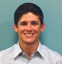 A person smiling in front of a teal background.