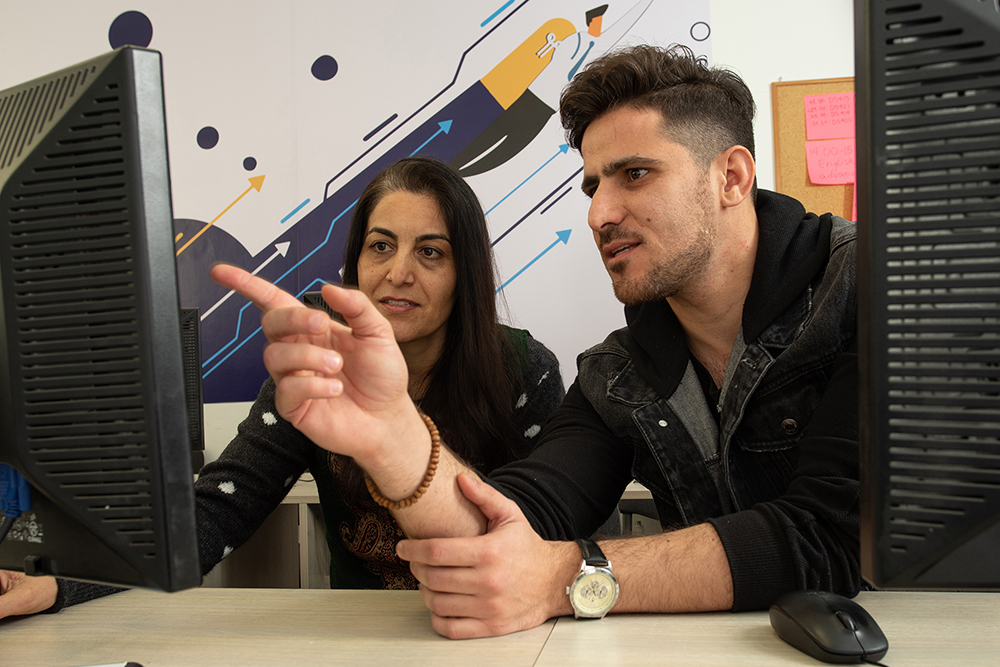 Two people discussing dataset labeling at computer screens. 