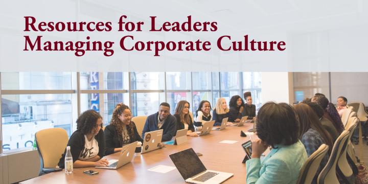 A business meeting with diverse group of participants sitting at a conference table with laptops and notebooks engaging in a conversation