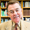 A person smiling in front of bookshelves.