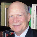 A person smiling in front of a bookshelf. image link to story