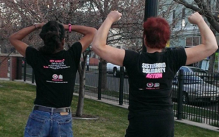 Two people flexing in Positive Women Network USA T-shirts outdoors.