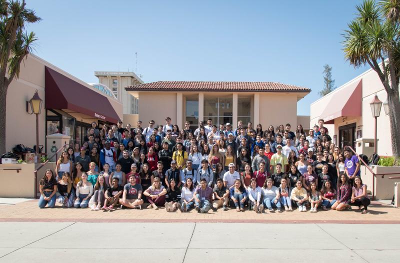 Large group of people posing in front of a building.