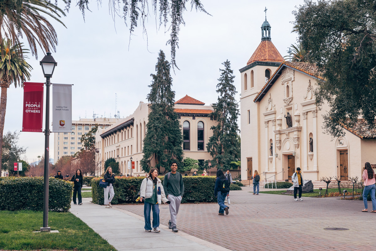 Students walking through campus in front of the mission church.