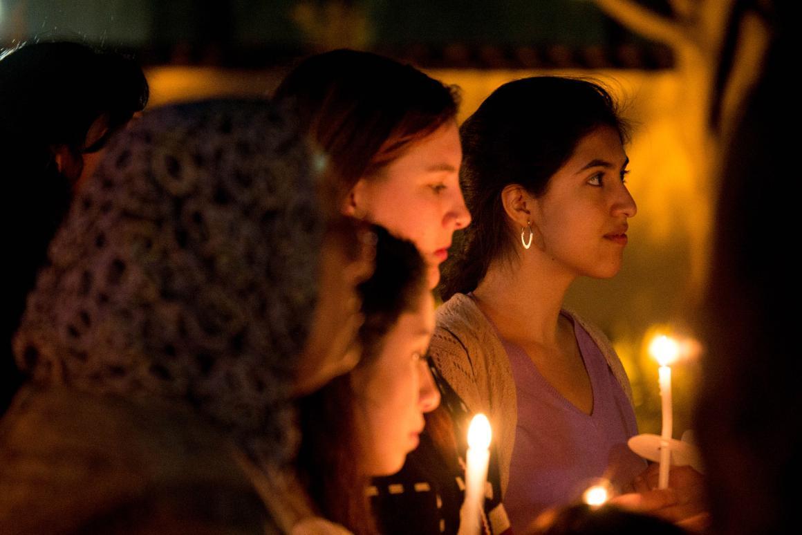 People holding candles during a vigil at night.