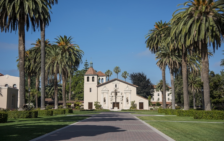 A picturesque campus building with palm trees lining the pathway.
