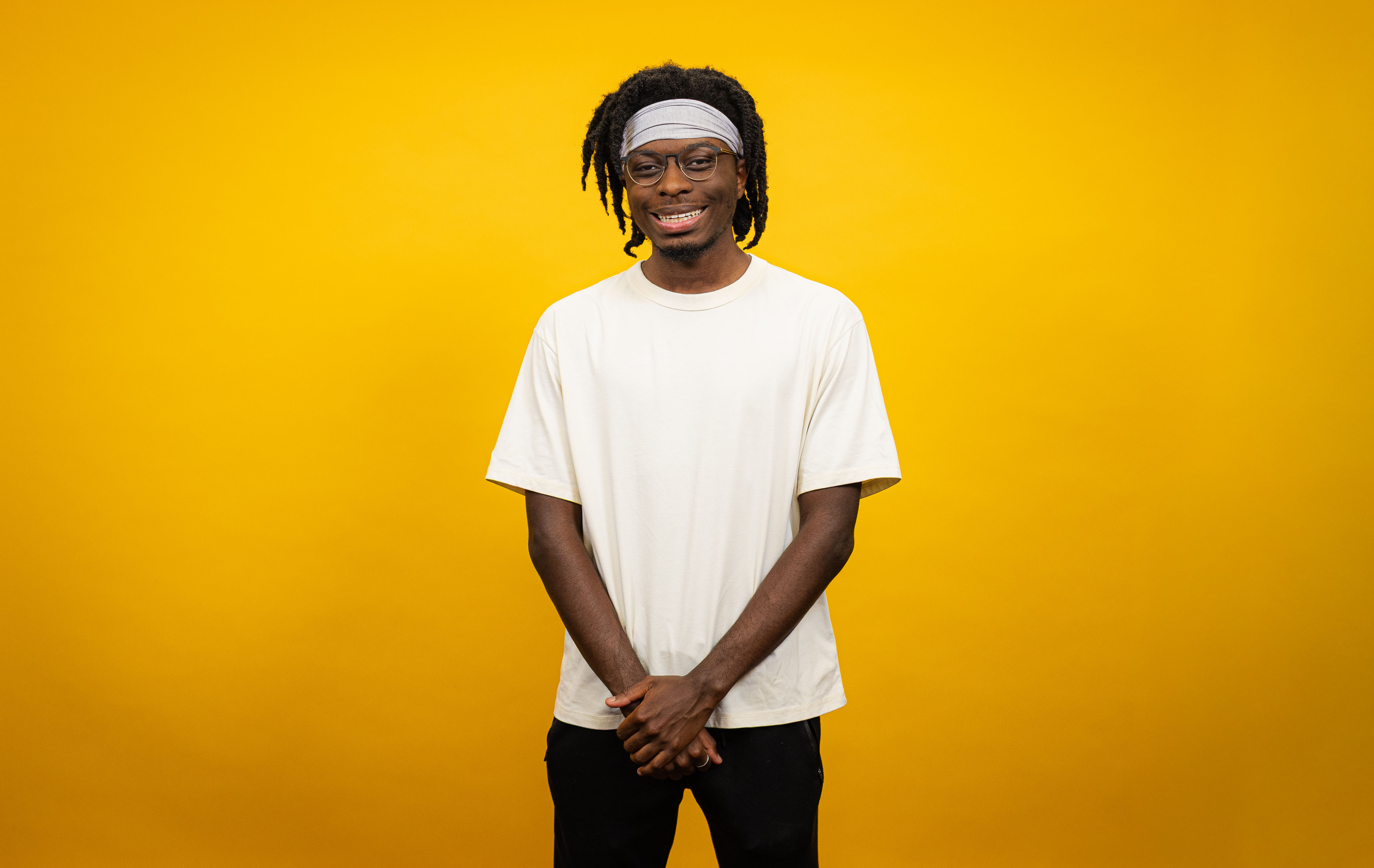 Young man stands in front of yellow backdrop.