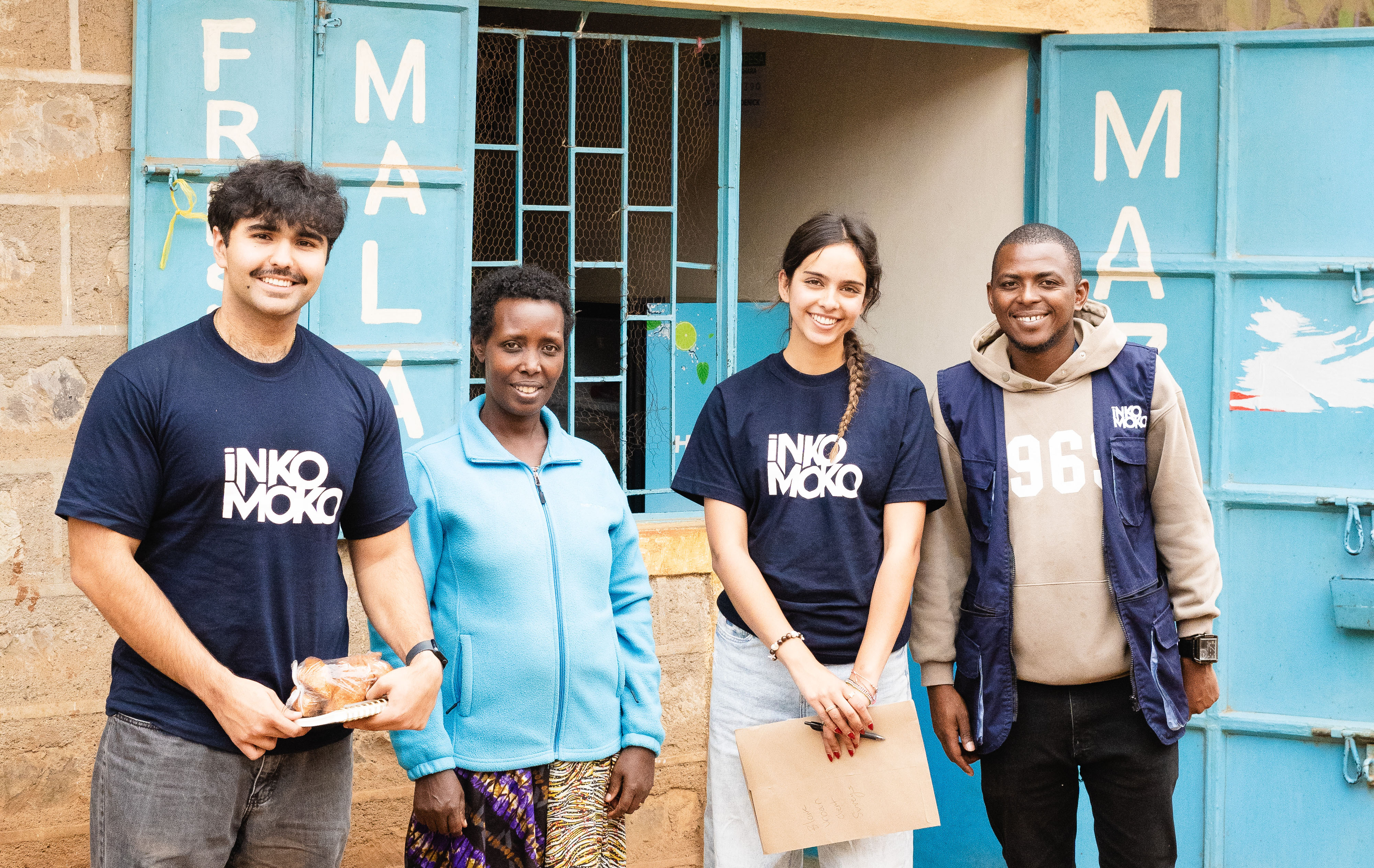 Men and women smile and stand in front of building.