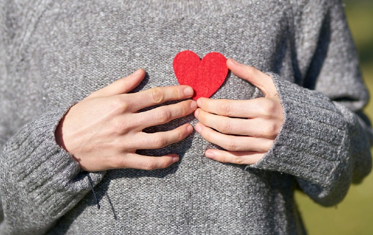 Closeup of students grey sweater holding up a felt heart.