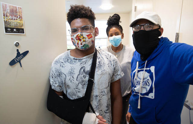 Ethan Evans, 24, stands next to the door of his room inside Graham Hall, with mom Sarah, center, and dad Jonathan Evans, right. Photo by Jim Gensheimer.