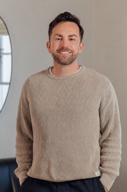 Kin app co-founder Kyle Alwyn stands in a beige sweater