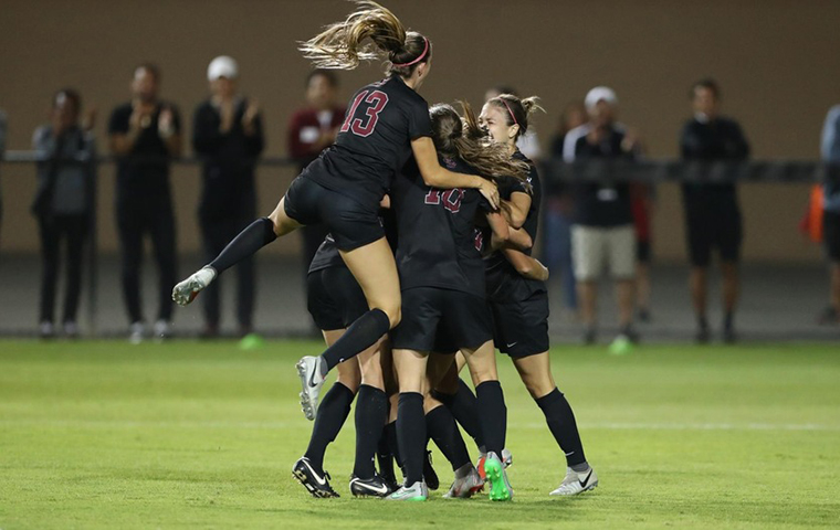 Womens soccer team celebrate in a circle. image link to story