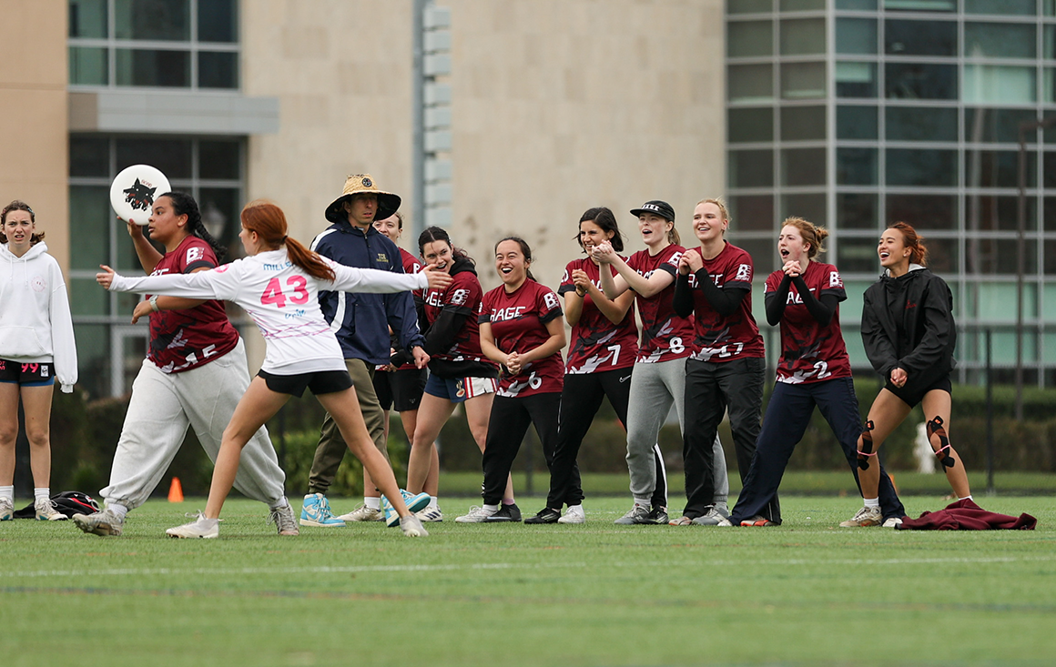 A group of Santa Clara Rage players cheer on their teammate from the sidelines of a game.