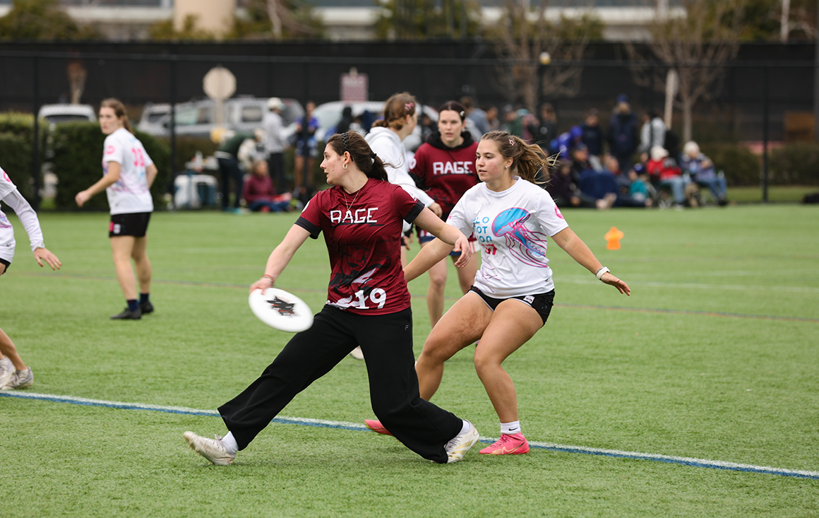 Two teams play ultimate frisbee on a grass field.
