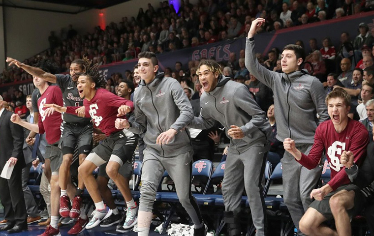 The mens basketball bench erupts in celebration against St. Mary’s