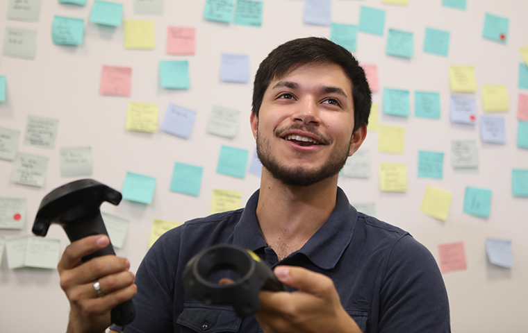 Miles Elliott 19 holds two virtual reality controllers