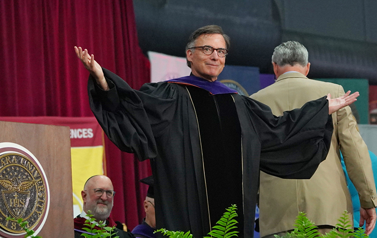 SCU President Kevin OBrien on stage at his presidential inauguration, hands out to his side