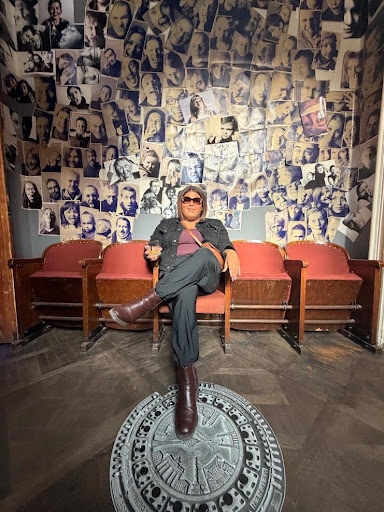Ruby Mendoza sitting on a couch with paper cutouts pasted on the wall